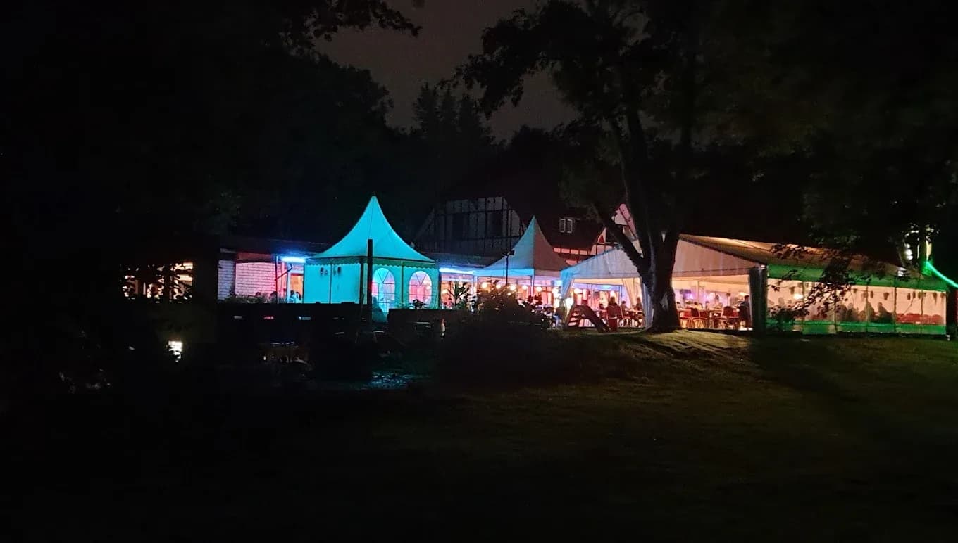 Lounge-Terrasse am Abend mit beleuchteten Zelten im Garten