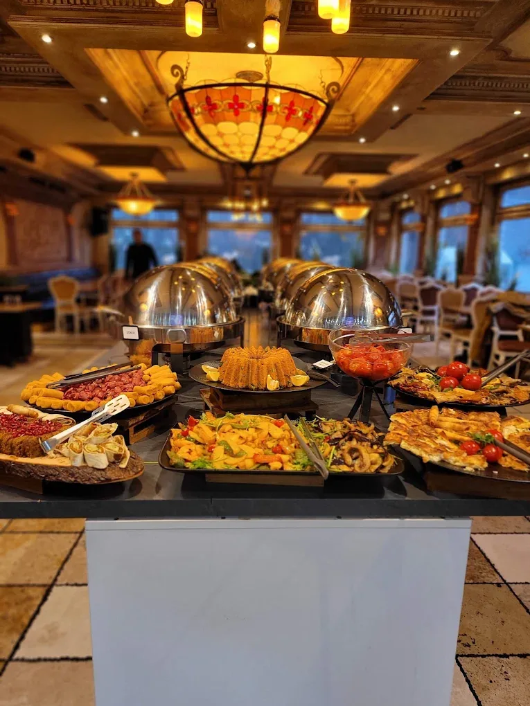 Buffet mit Warmhaltebehältern und Speisen unter einer Glasmosaik-Lampe